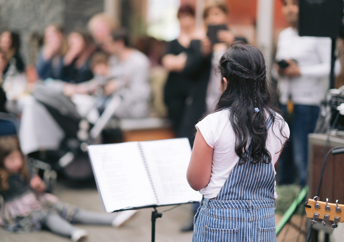 Young singer performing from a music stand in front of an audience, stage readiness and performance coaching in Melbourne
